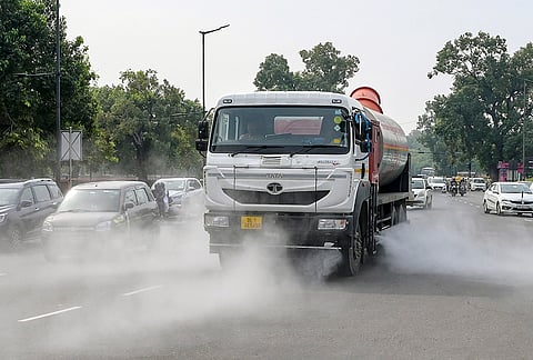 A sprinkler truck sprays water on a road near India Gate amid dust conditions, in New Delhi.