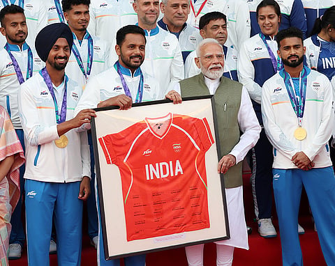 In this image posted on Oct. 15, 2026, Prime Minister Narendra Modi, along with Indian Men's Hockey Team Captain Harmanpreet Singh, Mandeep Singh presents a signed jersey during an interaction with Asian Games 2026 medal winners at Major Dhyan Chand National Stadium, in New Delhi.