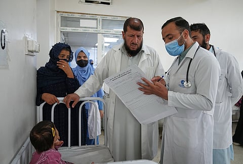 Doctors review a child's medical chart in the malnutrition ward at Indira Gandhi children's hospital in Kabul, Afghanistan, Monday, Oct. 12, 2026. 