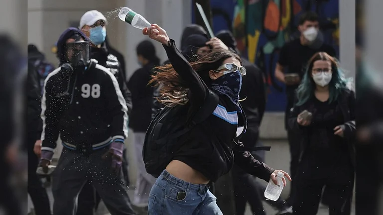 A young protester throws a plastic bottle towards riot police during clashes in Tirana, Albania - AP Photo/Hameraldi Agolli
