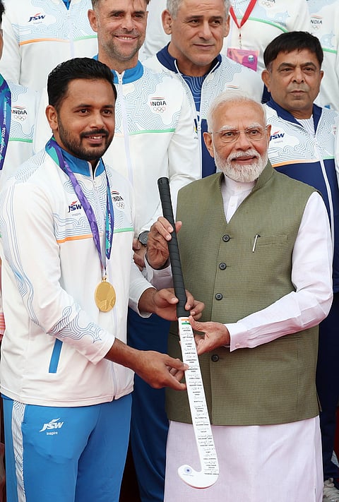 In this image posted on Oct. 15, 2026, Prime Minister Narendra Modi is presented a signed hockey stick by Indian Men's Hockey Team Captain Harmanpreet Singh during an interaction with Asian Games 2026 medal winners at Major Dhyan Chand National Stadium, in New Delhi.