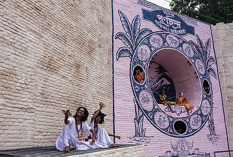 Artists perform in front of a community Durga Puja pandal themed on the traditional annual almanac (Panjika) ahead of the Durga Puja festival, in Kolkata, West Bengal, Wednesday, Oct. 14, 2026. 
