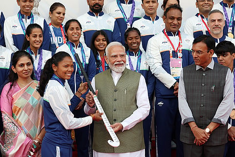 In this image posted on Oct. 15, 2026, Prime Minister Narendra Modi is presented a hockey stick by Indian Women's Hockey Team Captain Salima Tete during an interaction with Asian Games 2026 medal winners at Major Dhyan Chand National Stadium, in New Delhi, Thursday, Oct. 15, 2026. Union Minister for Youth Affairs and Sports Mansukh Mandaviya (R) and Minister of State for Youth Affairs and Sports Raksha Khadse (L) are also seen.