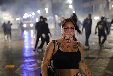 A woman covering her face walks past during an anti-government demonstration in Tirana, Albania, Friday, Oct. 16, 2026. 
