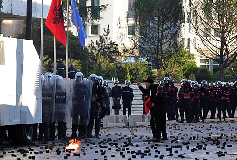 A man with a child shouts toward riot police during an anti-government demonstration in Tirana, Albania, Friday, Oct. 16, 2026. 

