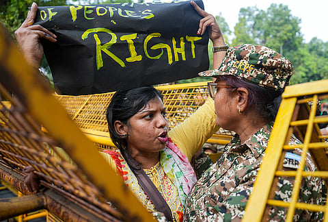 A demonstrator holding a placard speaks with a security personnel during the 'Reclaim Jantar Mantar' protest organized by Justice Morcha, in New Delhi, Saturday, Oct. 17, 2026. 