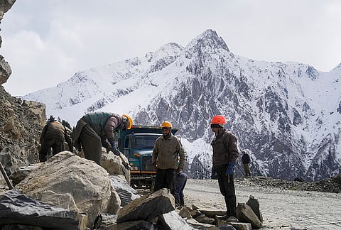 Beacon workers clear stones from the Srinagar-Leh National Highway near Zojila Pass, as the snowclad mountains were seen in the background, in Jammu and Kashmir, Saturday, Oct. 17, 2026. 
