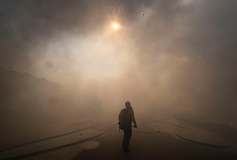 The sun is obscured by smoke as firefighters work to save structures on Via La Mirada during the Norte fire in San Clemente, California on Friday, Oct. 16, 2026. 