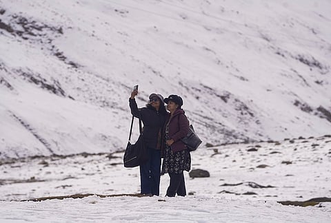 Tourists click photographs against the backdrop of snow-capped mountains following a fresh spell of snowfall near Zojila Pass along the Srinagar-Leh National Highway in Jammu and Kashmir, Saturday, Oct. 17, 2026. 

