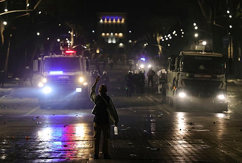 A protester gestures as police water cannons stand ready during an anti-government demonstration in Tirana, Albania, Friday, Oct. 16, 2026. 
