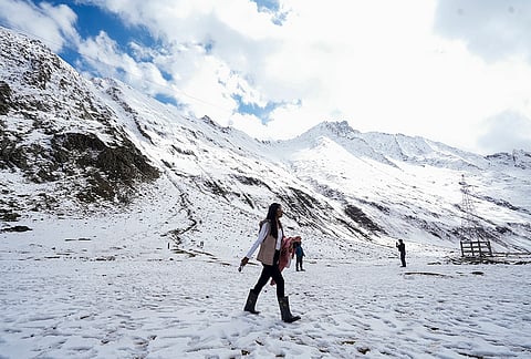 A woman walks across a snow-covered landscape following a fresh spell of snowfall near Zojila Pass along the Srinagar-Leh National Highway, in Jammu and Kashmir, Saturday, Oct. 17, 2026. 
