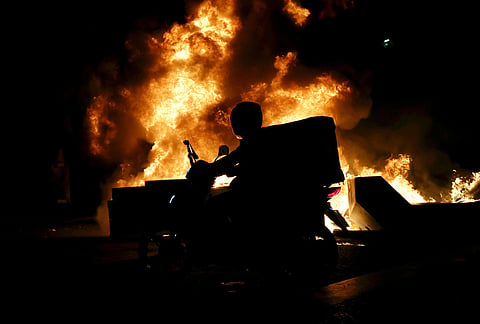 A delivery driver passes a burning barricade during an anti-government demonstration in Tirana, Albania, Friday, Oct. 16, 2026. 
