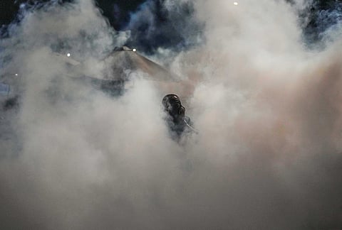 A vendor covers his face to shield himself from the smoke as a health worker fumigates a market to control mosquitoes and prevent the spread of malaria following reports of several cases in Panama City.