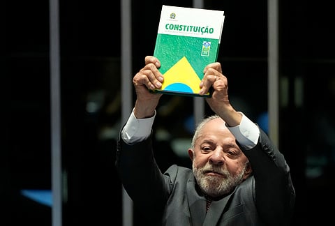 Brazilian President Luiz Inácio Lula da Silva, who is running for reelection, holds up a copy of the Constitution during a congressional session to enact an end to the six-day workweek in Brasília, Brazil.
