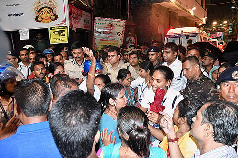 People gather outside as police officers set up a barricade at the entrance to a worship venue for the Hindu festival of Durga Puja following a stampede, in Kolkata, India.