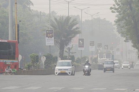 Commutters move along a road amid hazy conditions, in Navi Mumbai.
