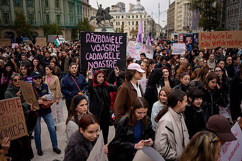 A woman holds a placard reading "Your wars, our corpses" during a protest aiming to raise awareness to the violence and prejudice against women in Romanian society, in Bucharest, Romania, Saturday, Oct. 17, 2026.