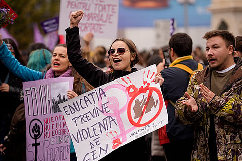 A woman holds a placard reading "Education prevents gender violence" during a protest aiming to raise awareness to the violence and prejudice against women in Romanian society, in Bucharest, Romania, Saturday, Oct. 17, 2026.