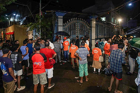 Volunteers and people gather outside the Durga Puja pandal following a stampede-like situation after an exit gate collapsed due to heavy crowd pressure, in Kolkata, Saturday, Oct. 17, 2026.