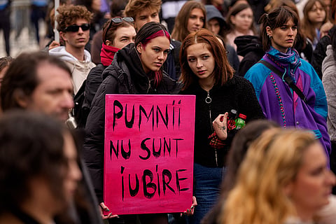 Women hold a placard reading "Fists are not love" during a protest aiming to raise awareness to the violence and prejudice against women in Romanian society, in Bucharest, Romania, Saturday, Oct. 17, 2026.