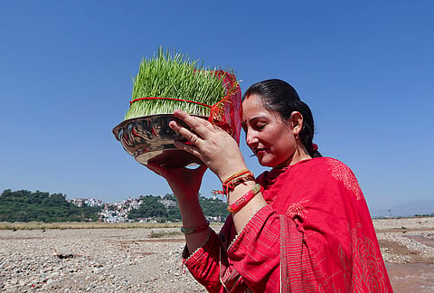 A devotee holds a pot of grown barley saplings to perform immersion rituals at Har Ki Pauri along the Tawi River on the concluding day of the Navratri festival, in Jammu.
