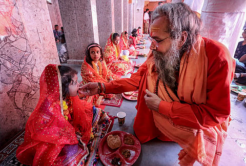 Secretary of Shri Panchayati Mahanirvani Akhara, Mahant Yamuna Puri, offers food to a young girl during 'Kanya Pujan' rituals at Mahanirvani Akhara, in Prayagraj.
