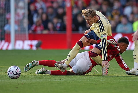 Nottingham Forest's Dan Ndoye, bottom, challenges for the ball with Arsenal's Martin Odegaard during the English Premier League soccer match between Nottingham Forest and Arsenal in Nottingham, England, Sunday, Oct. 18, 2026.
