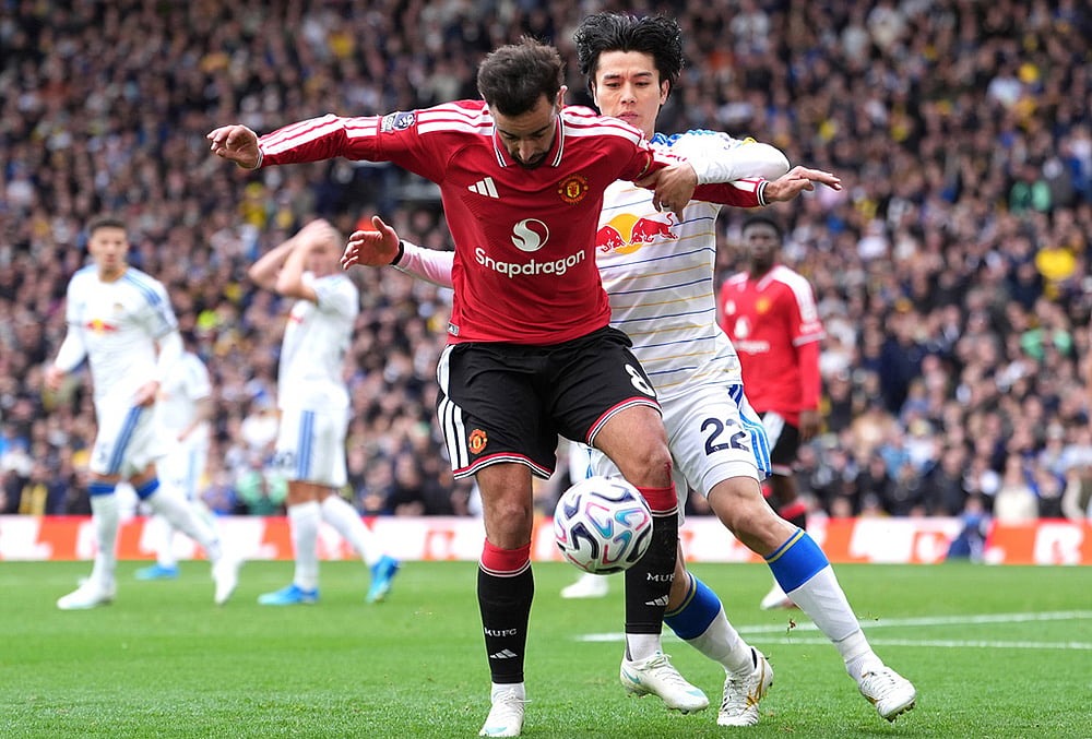Manchester United's Bruno Fernandes, left, and Leeds United's Ao Tanaka battle for the ball during the English Premier League soccer match between Leeds United and Manchester United in Leeds, England, Sunday, Oct. 18, 2026.  - | Photo: Annabel Lee-Ellis/PA via AP