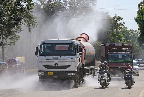 An anti-smog gun truck sprays water on a road near India Gate to curb dust pollution amid vehicular traffic, in New Delhi.