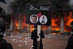Europe In Turmoil: Scenes Of Unrest From Across The Continent | Photo: AP/Laurent Cipriani : A protester holds a placard with a photo of French president Emmanuel Macron and a guillotine in front of a burning tourism office during a demonstration against rising living costs and in solidarity with students' grievances in Lyon, France, Saturday, Oct. 17, 2026.