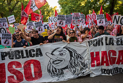 People march to demand more funding for public education during a protest in Madrid, Spain, Wednesday, Oct. 14, 2026. Banners reads in Spanish "Out Ayuso" in reference to Madrid's regional President, Isabel Díaz Ayuso. 
