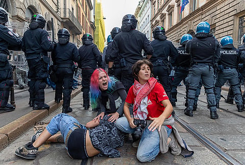 Demonstrators get shelter behind the police after clashes occurred during a protest against the high cost of living, in Milan, Italy, Saturday Oct. 17, 2026. 
