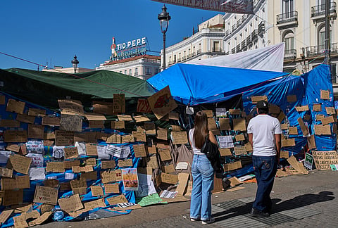 A couple reads messages at a makeshift camp set up by protesters demanding stronger laws to protect renters in Puerta del Sol square in Madrid, Spain, Friday, Oct. 16, 2026. 
