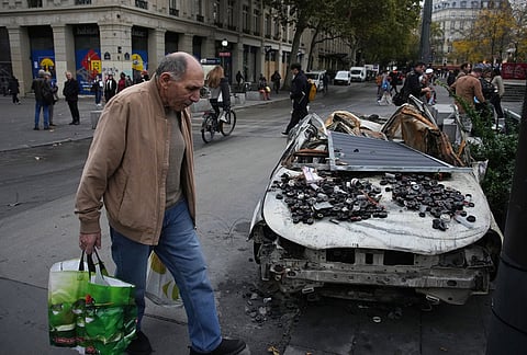 A man walks past a burned-out car after a quiet night Monday under curfew, the first since weekend protests over the cost of living turned into rioting and looting across France, in Paris, Tuesday, Oct. 20, 2026. 
