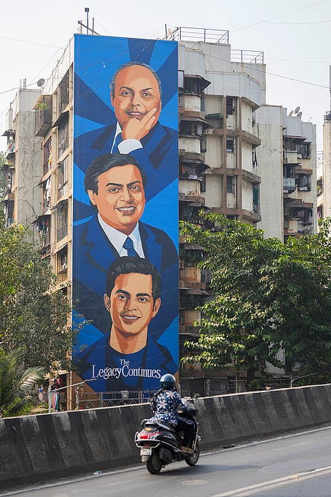 A commuter passes by a mural depicting three generations of the Ambani family painted on a residential building in Sion ahead of the proposed Reliance Jio IPO, in Mumbai, Maharashtra, Wednesday, Oct. 21, 2026. 
