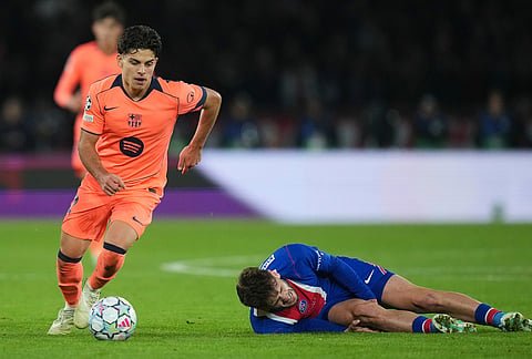 PSG's Khvicha Kvaratskhelia grimaces in pain after a challenges for the ball with Barcelona's Xavi Espart, left, during the Champions League opening phase soccer match between Paris Saint-Germain and FC Barcelona in Paris, Tuesday, Oct. 20, 2026. 