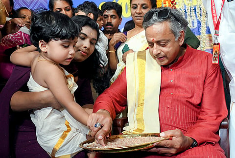 Congress MP Shashi Tharoor initiates a child into the world of letters during the 'Vidyarambham' ceremony, in Thiruvananthapuram, Keralam.