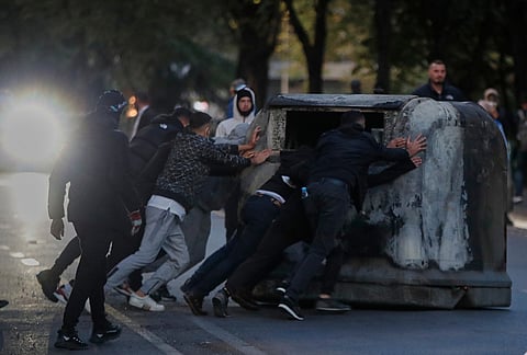 Protesters push a large garbage container during an anti-government protest in Tirana, Albania, Tuesday, Oct. 20, 2026. 