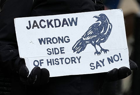 A protester holds a poster during a demonstration against the government’s approval of a natural gas project off Scotland's coast at the Department for Energy Security and Net Zero in London, Wednesday, Oct. 21, 2026. 