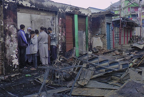 People gather in the aftermath of a fire incident in the Bhagwah market area on Wednesday, which gutted several shops, in Doda.

