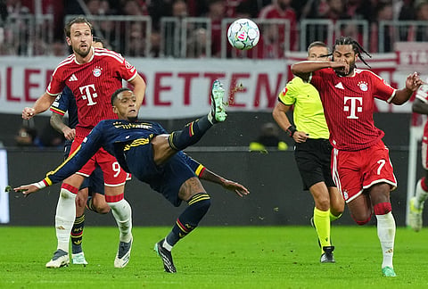 Arsenal's Ezri Konsa clears the ball in front of Bayern's Harry Kane during the UEFA Champions League soccer match between Bayern and Arsenal in Munich Germany, Wednesday, Oct. 21, 2026. 
