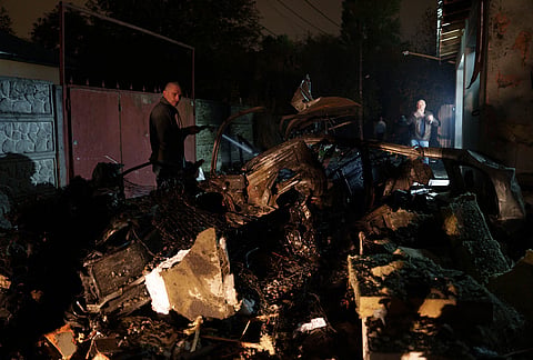 A local man puts out a fire of car destroyed in a Russian missile strike on a residential neighborhood in Kyiv, Ukraine, Wednesday, Oct. 21, 2026. 
