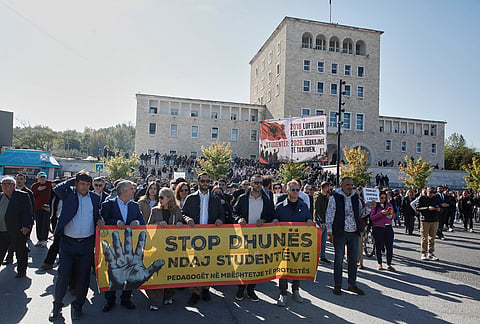 Teachers hold a banner reading in Albanian, "Stop violence against students," during an anti-government protest, with the prime minister's office in the background, in Tirana, Albania, Tuesday, Oct. 20, 2026. 
