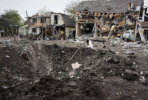A woman looks at a crater after a Russian missile strike in Kyiv, Ukraine, Thursday, Oct. 22, 2026. 