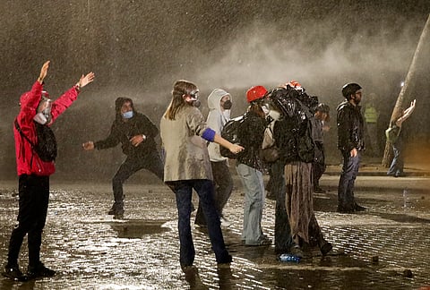 Anti-government protesters stand amid the spray from a police water canon in Tirana, Albania, late Tuesday, Oct. 20, 2026. 

