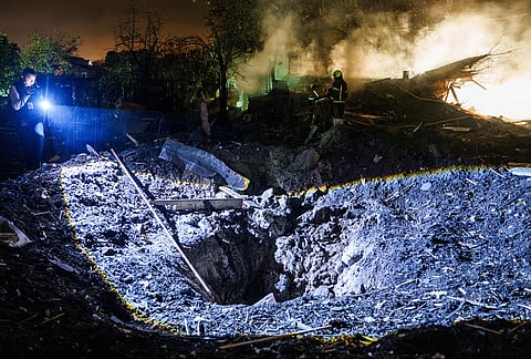 A journalist films a crater after a Russian missile strike on residential neighbourhood in Kyiv, Ukraine, Wednesday, Oct. 21, 2026. 