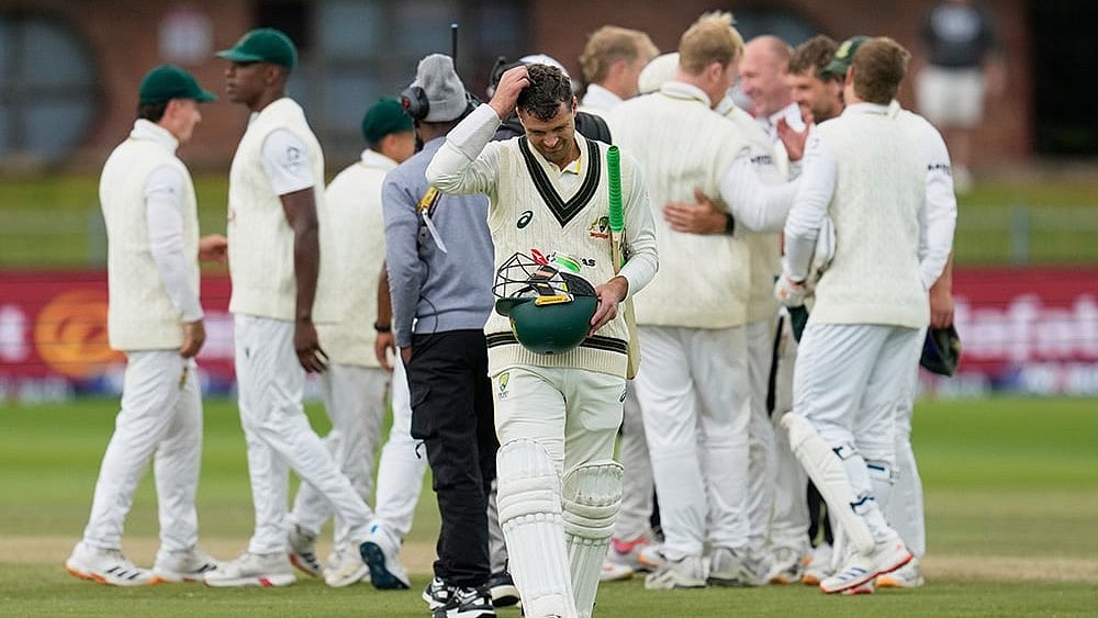 Photo: AP/Themba Hadebe : Australia's Alex Carey, center, walks off the field as South African players celebrate winning the second cricket test match between South Africa and Australia on day five, in Gqeberha, South Africa, Thursday, Oct. 22, 2026. 