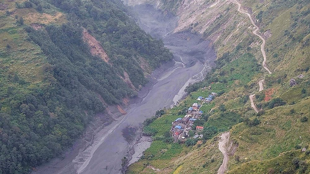 An aerial view shows mudslide debris and floodwaters overflowing the Budhi Gandaki river following a sudden flash flood triggered by a suspected landslide in the Chekampar area, in Gorkha district, Nepal, Sunday, Oct. 11, 2026.  - | Photo: PTI/Abhishek Maharjan