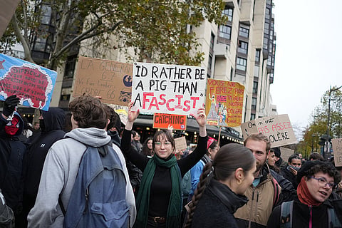 Protesters hold signs during a demonstration against rising living costs in Paris, Saturday, Oct. 24, 2026.