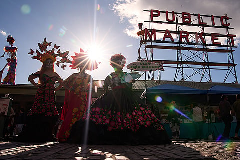 Catrinas pose for photos during a Día de Muertos celebration at Pike Place Market, Friday, Oct. 23, 2026, in Seattle.